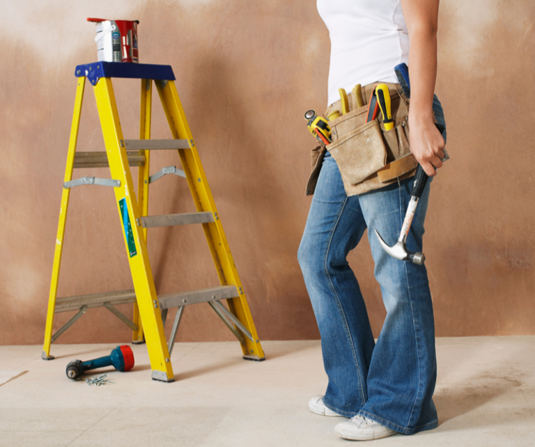 Woman wearing a toolbelt with a hammer and step ladder